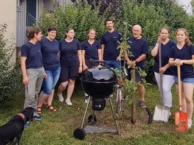 Das Team von Tier&auml;rzte Team Tiefenbach steht um den gepflanzten Baum. Daneben steht ein Grill.