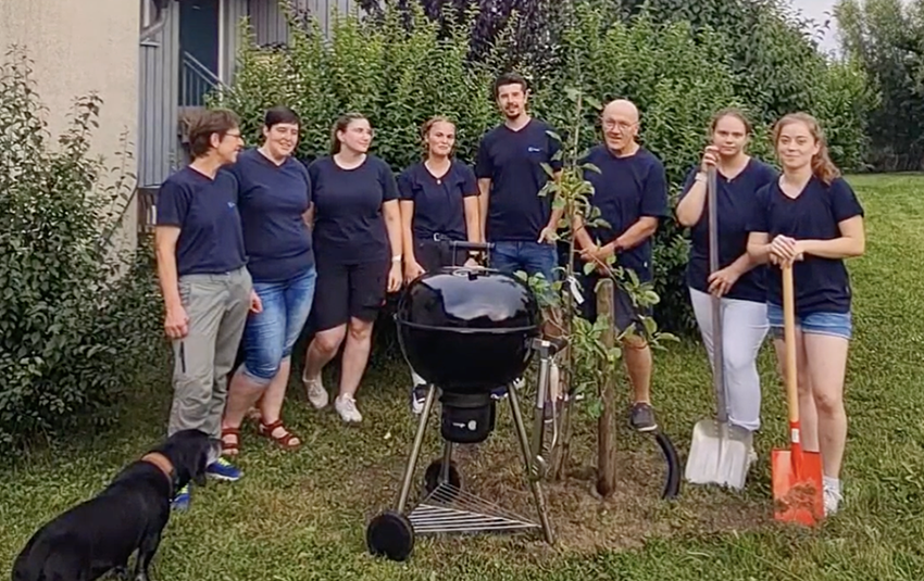 Das Team von Tierärzte Team Tiefenbach steht um den gepflanzten Baum. Daneben steht ein Grill.